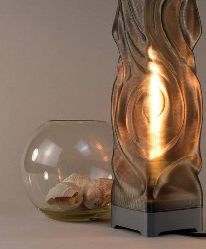 Decorative lamp with wavy glass design next to a glass bowl with shells on a neutral background