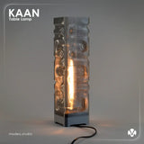Gray textured table lamp with 'KAAN' branding on a gray background with the light turned on. Created by MODEO Design