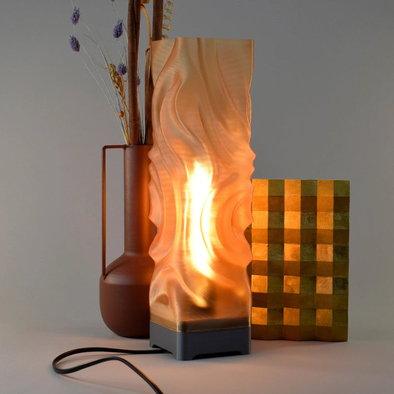 Decorative lamp with wavy design and a vase with dried flowers on a neutral background